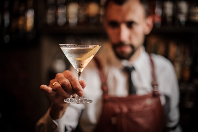 Bartender holding a transparent cocktail in the martini glass Bartender holding a transparent cocktail in the martini glass