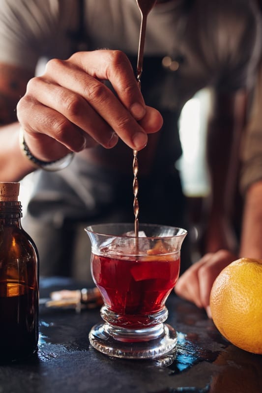 Bartender hand stirring a negroni cocktail Bartender hand stirring a negroni cocktail