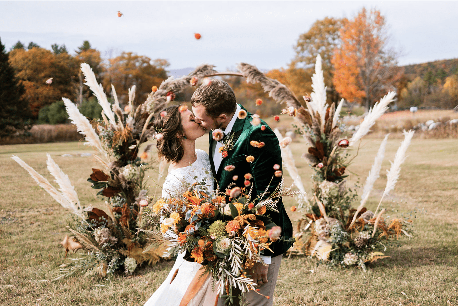 couple kissing after marriage ceremony with petals being thrown