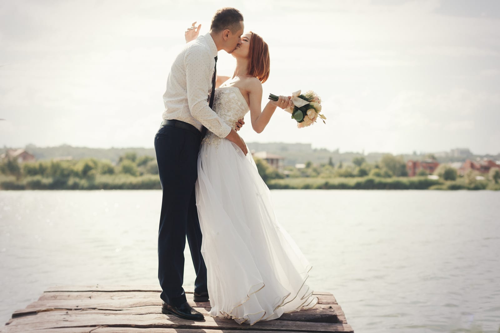 Wedding couple walking on bridge near lake on sunset at wedding day. Bride and groom in love Wedding couple walking on bridge near lake on sunset at wedding day. Bride and groom in love