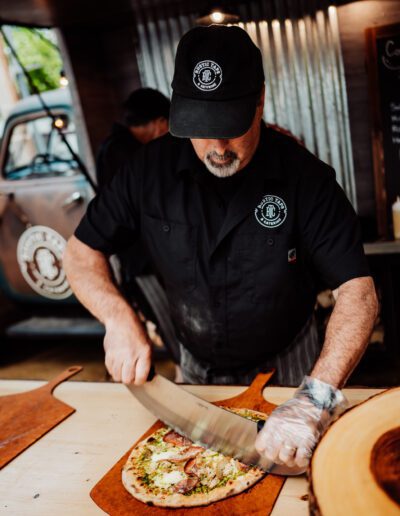 Employee cutting wood fired pizza