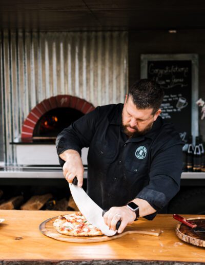 Rustic tap employee cutting pizza